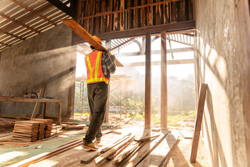 Fototapeta premium Carpenter holds wooden planks on construction site