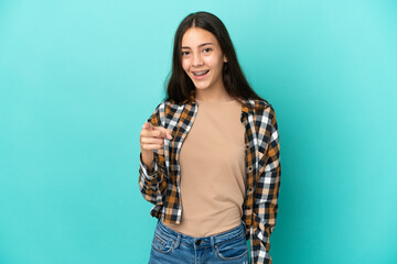 Young French woman isolated on blue background surprised and pointing front