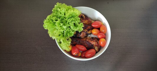 Grilled Chicken Drumstick with Rice in white bowl on black wooden floor from top view