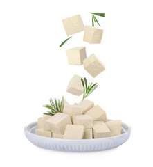 Cubes of raw tofu falling into plate on white background
