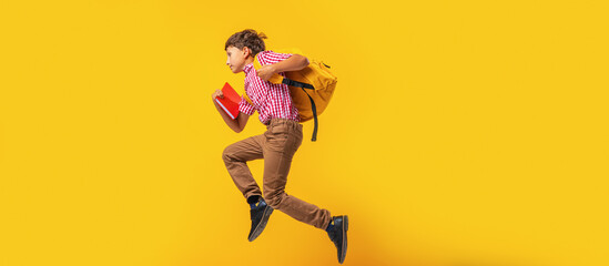 cheerful mischievous schoolboy in uniform with backpack runs on yellow background. Dynamic images...