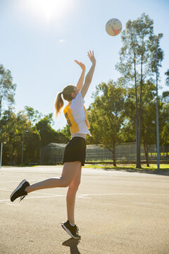 Vertical Shot Of Young Woman In Sporty Clothes Throwing A Ball In The Air With One Foot Raised