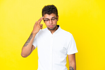 Young handsome Brazilian man isolated on yellow background with problems making suicide gesture