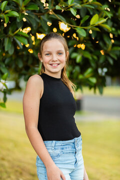 vertical portrait of smiling young tween girl against natural background of leaves