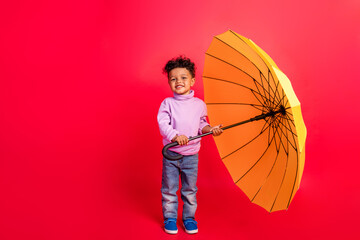 Full length body size view of nice cheerful preteen kid holding parasol cyclone isolated over bright red color background © deagreez