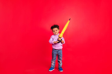 Full length body size view of attractive cheerful kid holding parasol kindergarten isolated over bright red color background