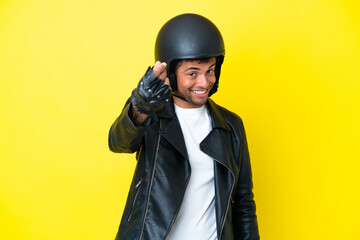 Young Brazilian man with a motorcycle helmet isolated on yellow background making money gesture