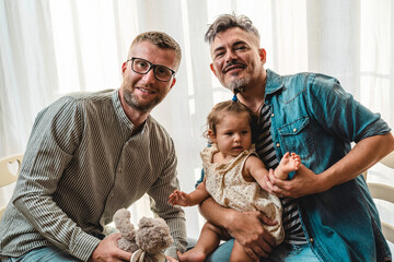 Portrait of happy LGBTQ family at home - Gay couple and their daughter - Diversity concept and LGBTQ family relationship