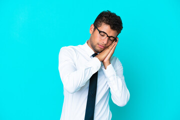 Young business Brazilian man isolated on blue background making sleep gesture in dorable expression
