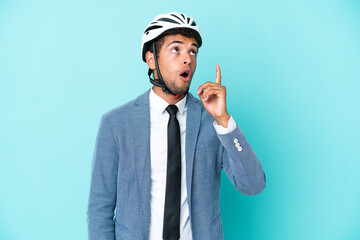 Young business Brazilian man with bike helmet isolated on blue background thinking an idea pointing the finger up