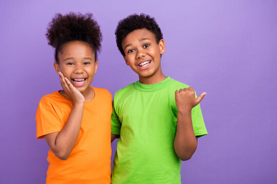 Photo of two young little afro kids happy positive smile point thumb empty space ad promo direct isolated over violet color background