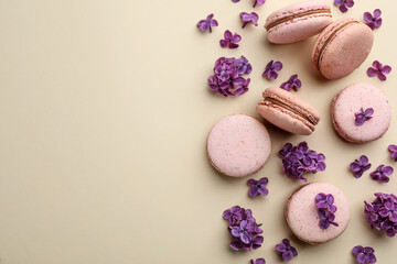 Fototapeta na wymiar Flat lay composition with macarons and lilac flowers on beige background. Space for text