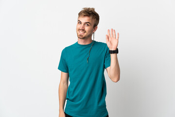 Young handsome man isolated on white background saluting with hand with happy expression