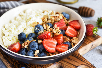 Breakfast - cottage cheese with berries and a cup of coffee, top view. Granola with nuts, honey and strawberries.