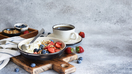 Obraz na płótnie Canvas Granola, honey, nuts and blueberries, strawberries for breakfast. Kitchen on concrete background.Breakfast - cottage cheese with berries and a cup of coffee.