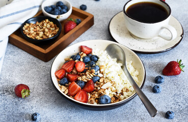 Granola, honey, nuts and blueberries, strawberries for breakfast. Kitchen on concrete background.Breakfast - cottage cheese with berries and a cup of coffee.