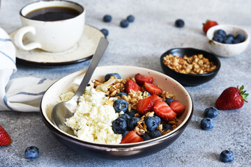 Breakfast - cottage cheese with berries and a cup of coffee, top view. Granola with nuts, honey and strawberries.