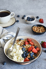 Breakfast - cottage cheese with berries and a cup of coffee, top view. Granola with nuts, honey and strawberries.