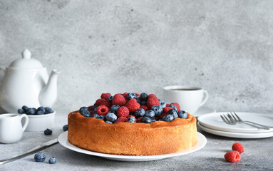 Vanilla pie with raspberries, blueberries on the kitchen table with a cup of coffee. Cheesecake with berries.