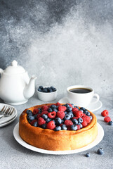Vanilla pie with raspberries, blueberries on the kitchen table with a cup of coffee. Cheesecake with berries.