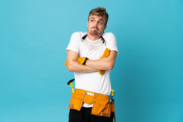 Young electrician man over isolated wall making doubts gesture while lifting the shoulders
