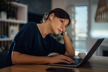 Overworked businesswoman working on laptop, at home.