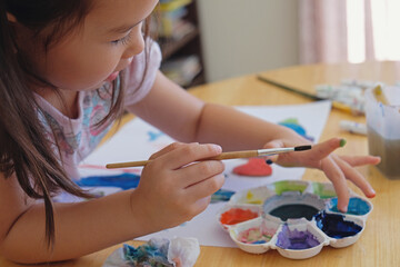 Little girl having fun painting at home