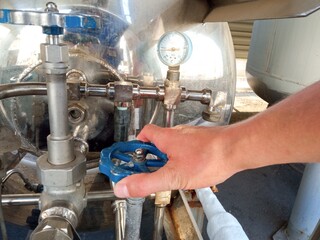 A man's hand opens the gas supply valve from a gas cylinder
