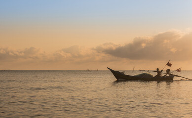 Silhouette of fishing boat and man in morning in Thailand, Nature and culture concept.