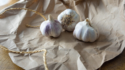 Garlic, garlic cloves placed on brown paper over rustic wood, small depth of field, black background, selective focus.