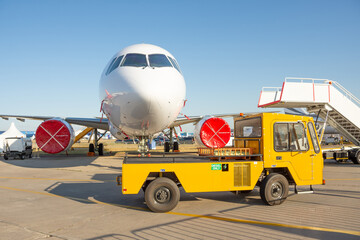 Airplane parked with a gangway, yellow ground service truck driving ahead.