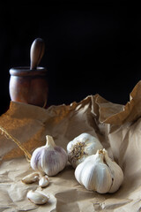 Garlic, garlic cloves placed on brown paper over rustic wood, small depth of field, black background, selective focus.