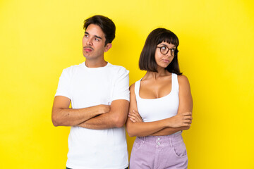 Young mixed race couple isolated on yellow background with confuse face expression while bites lip