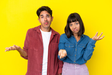 Young mixed race couple isolated on yellow background unhappy and frustrated with something because not understand something