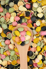 Italian rainbow arcobalena pasta. Suitable for vegan and vegetarian diet, gluten free, high in vitamins, minerals. In wooden spoon and forming a background. Flat lay, top view.