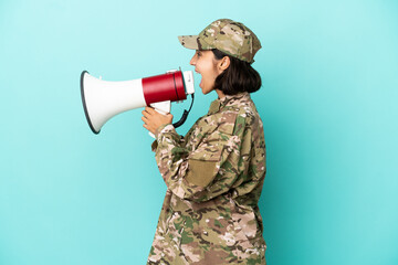Fototapeta premium Military mixed race woman isolated on blue background shouting through a megaphone