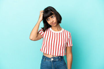 Young mixed race woman isolated on blue background having doubts while scratching head