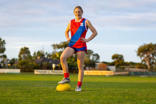 Teenage Girl In Uniform Standing On Football Oval With Foot On Ball