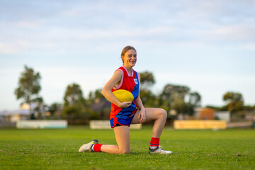 one football player on field kneeling holding football
