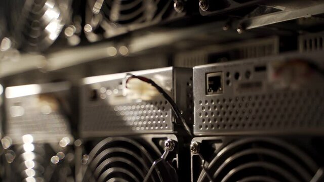Bitcoin ASIC miners in warehouse. ASIC mining equipment on stand racks for mining cryptocurrency in steel container. Fan grills and ventilators for cooling electronics. Air coolers.