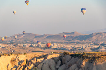 many hot air balloons in the sky over a valley in Cappadocia, Nevsehir, Turkey in a beautiful summer day