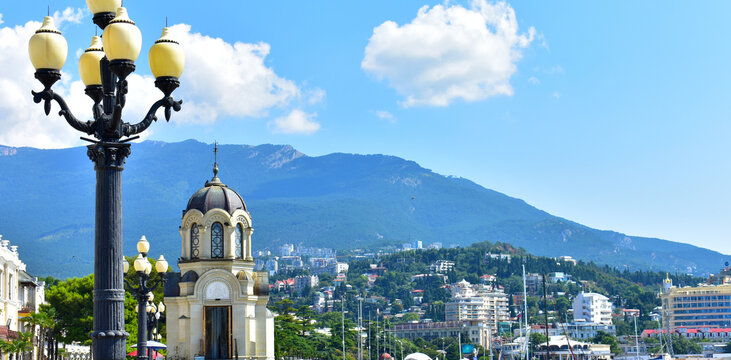 Summer view of the Yalta embankment with a church shop, lantern and mountains, Crimea, Yalta, August 2021.