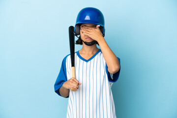 Baseball mixed race player woman with helmet and bat isolated on blue background covering eyes by...