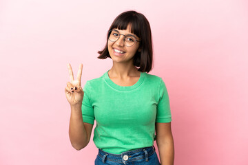 Young mixed race woman isolated on pink background smiling and showing victory sign