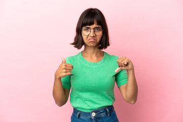 Young mixed race woman isolated on pink background making good-bad sign. Undecided between yes or not