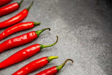 Red chili pepper arranges on the gray background.