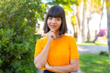 Fototapeta premium Young brunette woman at outdoors in a park With happy expression