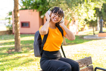 Young student woman in a park listening music