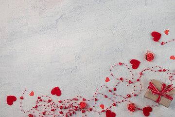 gift with red ribbon on white textured background with red beads with hearts. background for valentine's day. flat lay