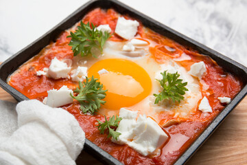 Fried eggs with tomatoes and cheese in a frying pan. Shakshuka, a Jewish dish.
